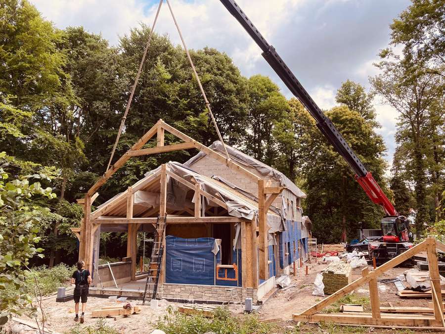 Ferme de chêne levée à la grue au-dessus d'une maison en forêt